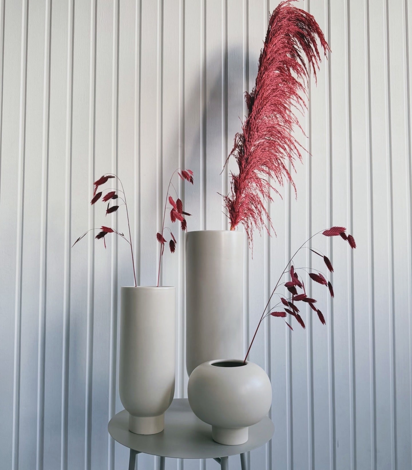 Creamfärgade keramikvaser på sidobord med röda velvet pampas och torkade röda kvistar mot ljus panelvägg, modern skandinavisk inredning och styling från Torrdecor