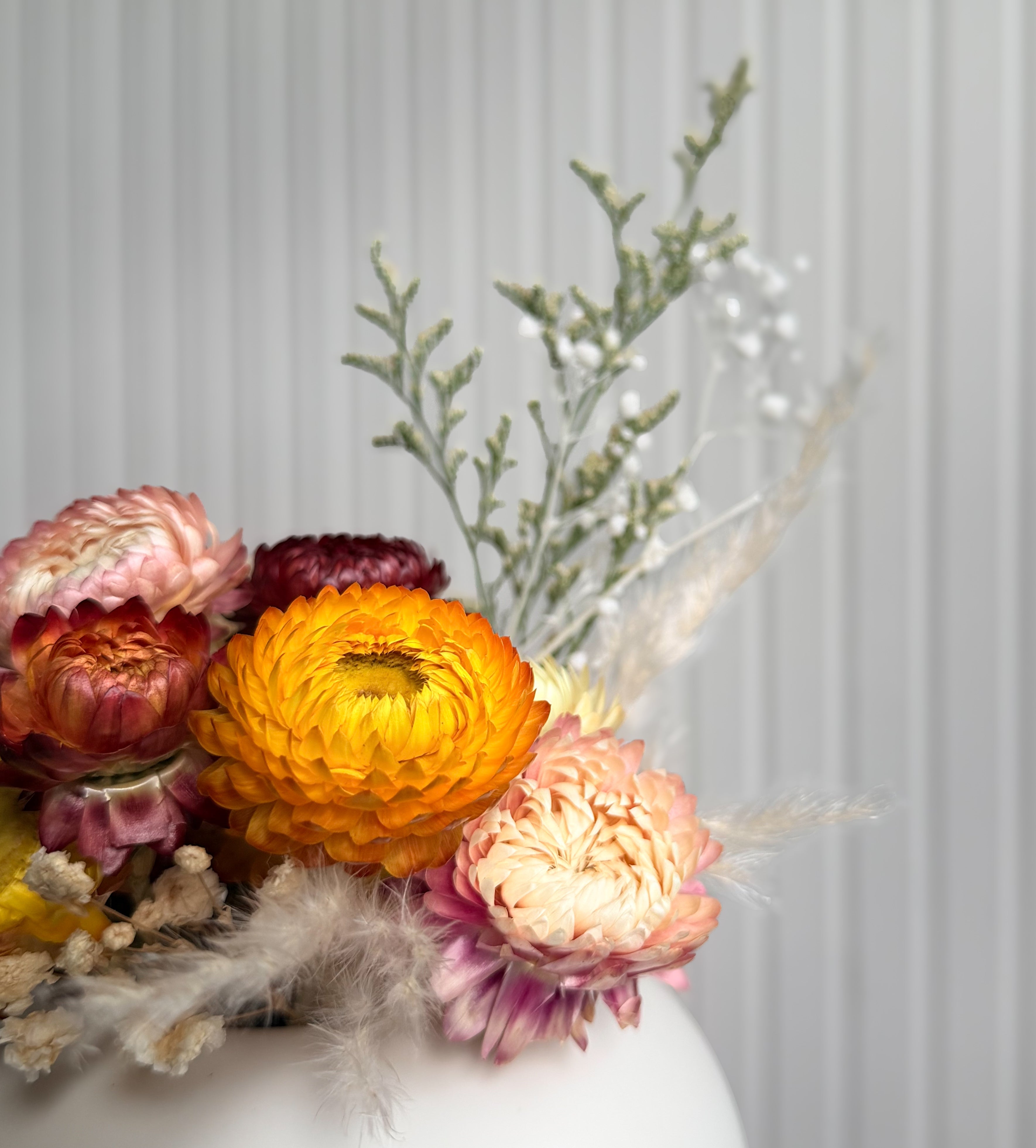 Närbild på minibuketten i gåvoset 'MORGONSTUND' med gula, orange, rosa och vinröda blommor.