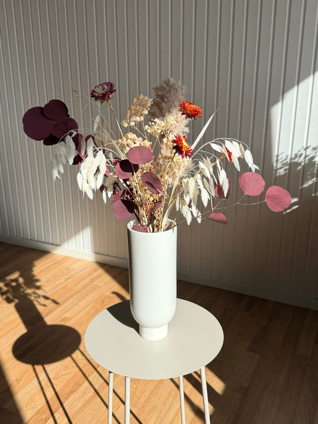 Mixbunt ’SKYMNING’ i vinrött, beige och orange, stylad i vit vas